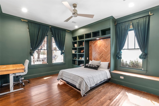 bedroom with ceiling fan, multiple windows, wood finished floors, and baseboards