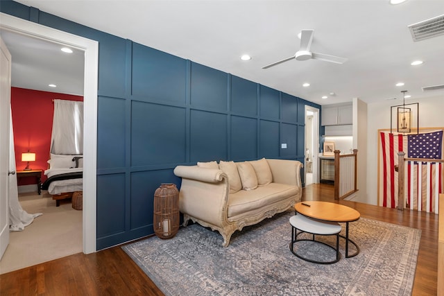 living area featuring dark wood-style flooring, visible vents, and a decorative wall