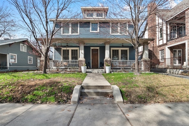 traditional style home featuring a porch, a front yard, and brick siding