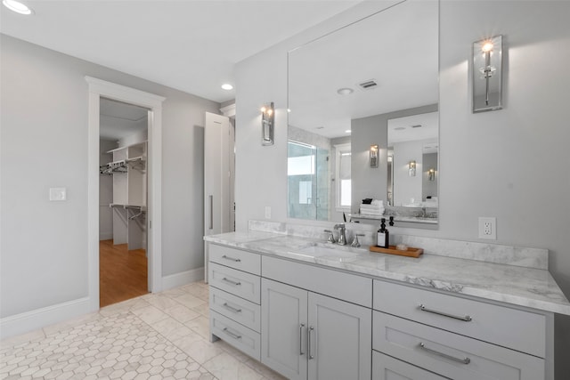 bathroom with vanity, visible vents, baseboards, a shower stall, and a walk in closet