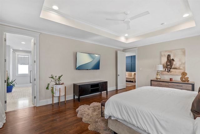 bedroom featuring baseboards, a tray ceiling, dark wood-type flooring, and ornamental molding