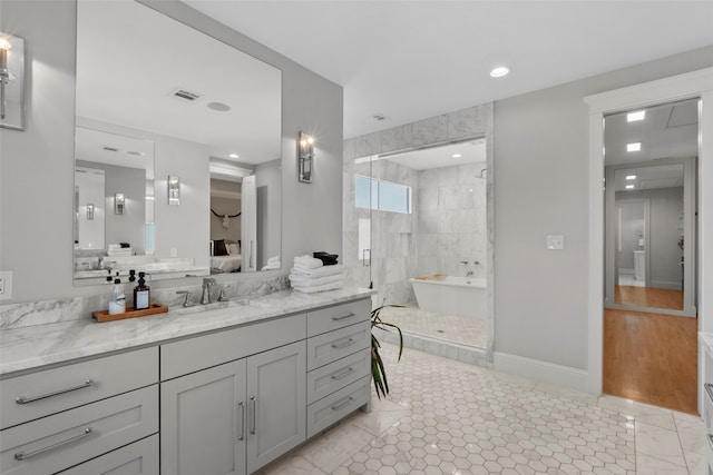 bathroom with a soaking tub, visible vents, ensuite bathroom, vanity, and baseboards