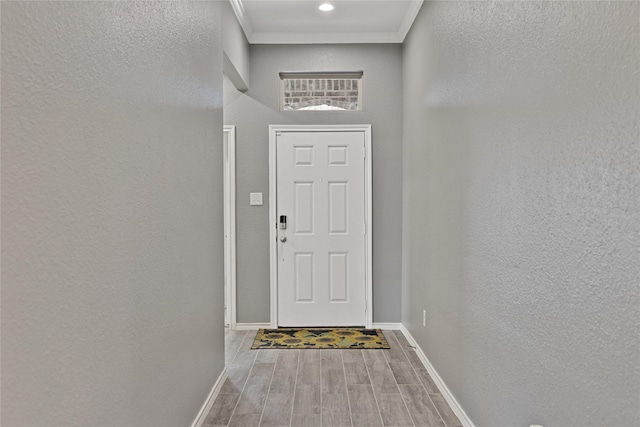 doorway featuring crown molding, wood finished floors, and a textured wall