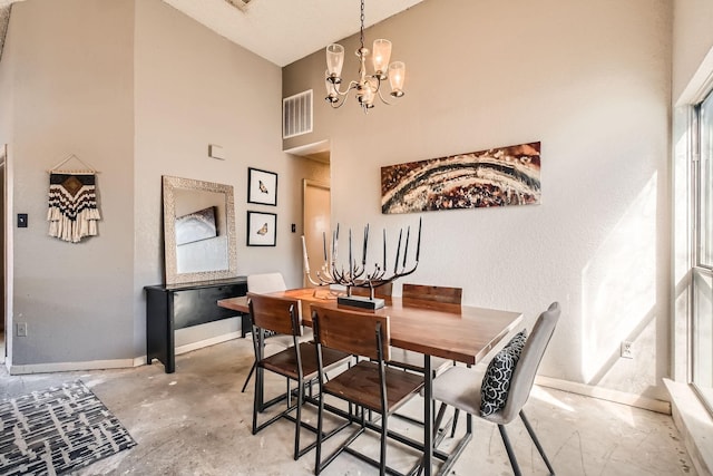 dining area featuring unfinished concrete flooring, visible vents, a towering ceiling, an inviting chandelier, and baseboards