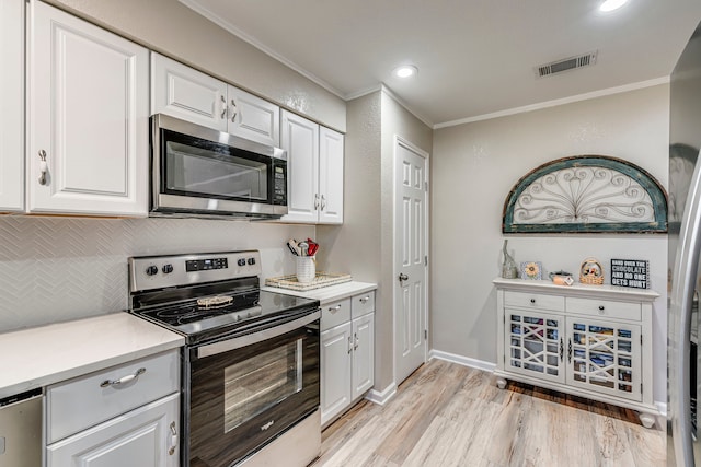 kitchen featuring visible vents, stainless steel appliances, crown molding, light countertops, and white cabinetry