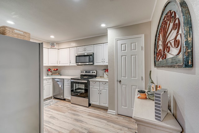 kitchen with appliances with stainless steel finishes, light countertops, crown molding, light wood-style floors, and white cabinetry