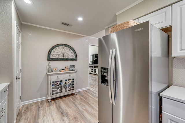 kitchen with stainless steel fridge, visible vents, light countertops, crown molding, and white cabinetry