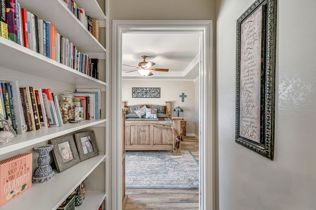 hall featuring crown molding, baseboards, and wood finished floors