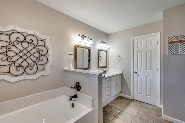 full bath with a textured wall, a textured ceiling, vanity, baseboards, and a bath