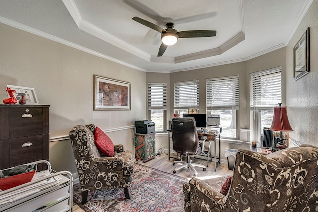 office with light wood-type flooring, a wealth of natural light, a raised ceiling, and crown molding