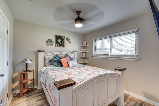 bedroom with ceiling fan, baseboards, and wood finished floors