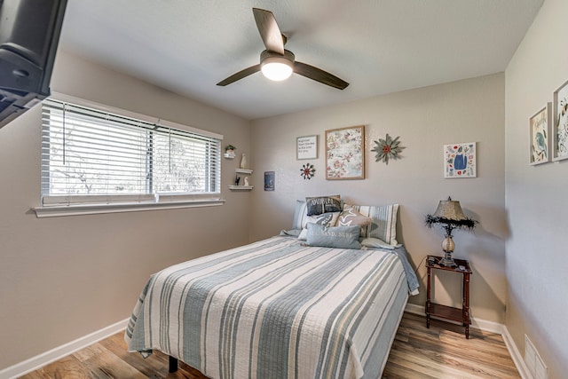 bedroom featuring baseboards, visible vents, ceiling fan, and light wood finished floors