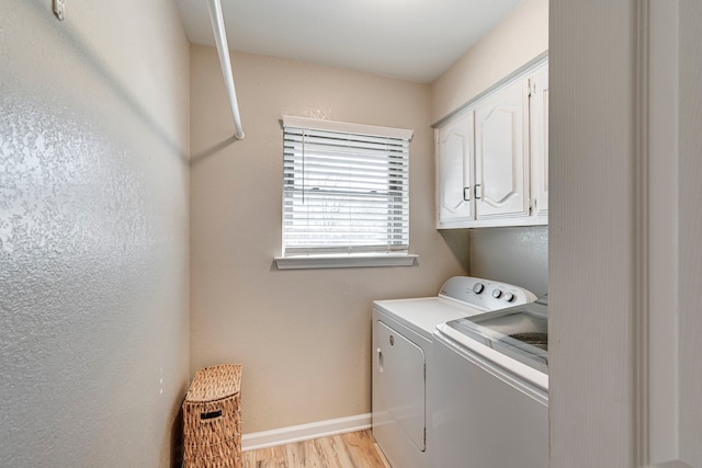 laundry area featuring light wood-style floors, cabinet space, baseboards, and separate washer and dryer