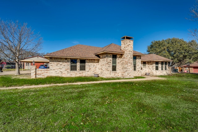 rear view of property featuring brick siding, a lawn, and a chimney