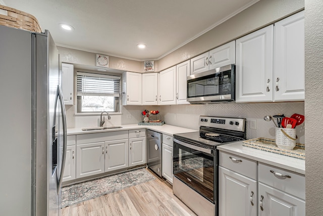 kitchen featuring white cabinets, appliances with stainless steel finishes, light countertops, crown molding, and a sink