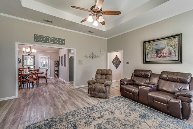 living area featuring ornamental molding, wood finished floors, a raised ceiling, and visible vents