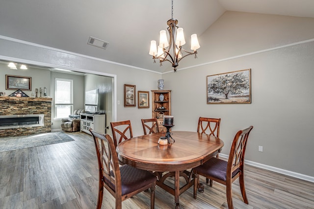 dining area featuring lofted ceiling, visible vents, a fireplace, and wood finished floors