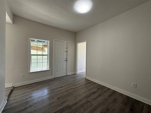 unfurnished room featuring dark wood-type flooring and baseboards