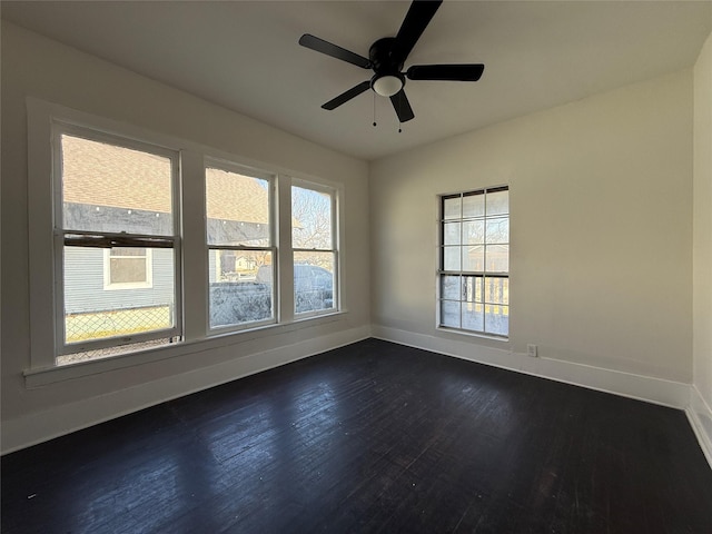 spare room featuring ceiling fan, dark wood-style flooring, and baseboards