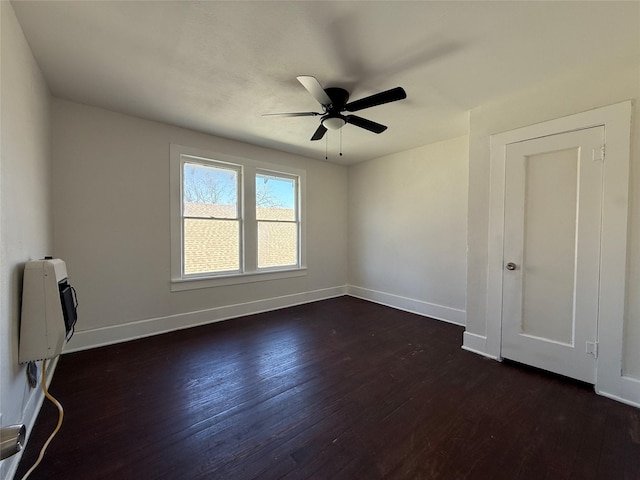 empty room with ceiling fan, dark wood-style flooring, and baseboards