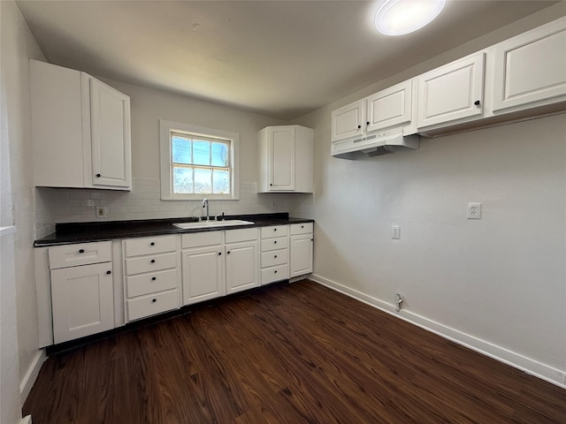 kitchen with dark wood-type flooring, a sink, white cabinets, decorative backsplash, and dark countertops