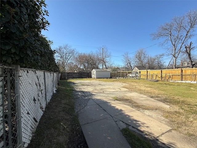 view of yard featuring an outbuilding, a fenced backyard, and a storage shed