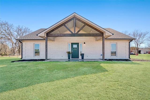 back of house with roof with shingles, a lawn, and brick siding