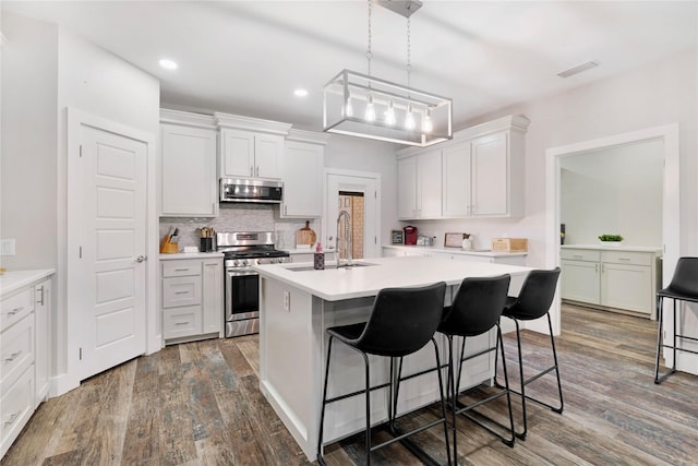 kitchen featuring white cabinets, appliances with stainless steel finishes, light countertops, and a kitchen breakfast bar