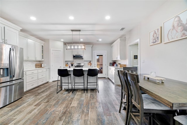 kitchen featuring stainless steel appliances, hanging light fixtures, light countertops, and white cabinetry