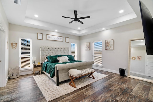 bedroom featuring recessed lighting, dark wood-type flooring, visible vents, baseboards, and a tray ceiling