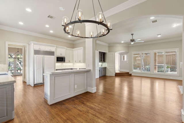 kitchen with black microwave, arched walkways, visible vents, white cabinets, and light countertops