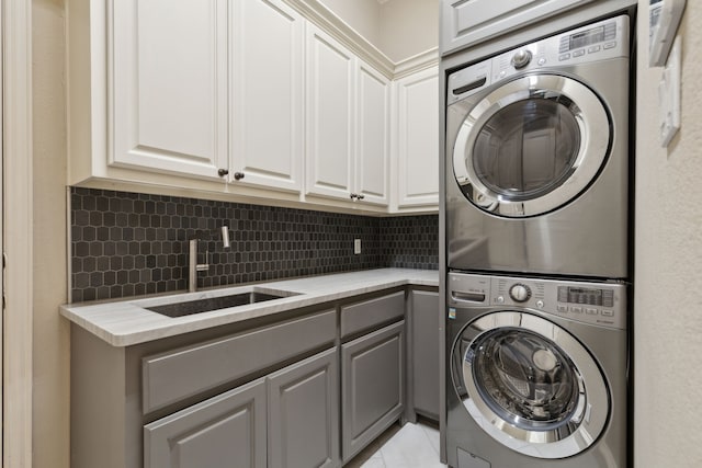 laundry area with a sink, stacked washer and dryer, and cabinet space