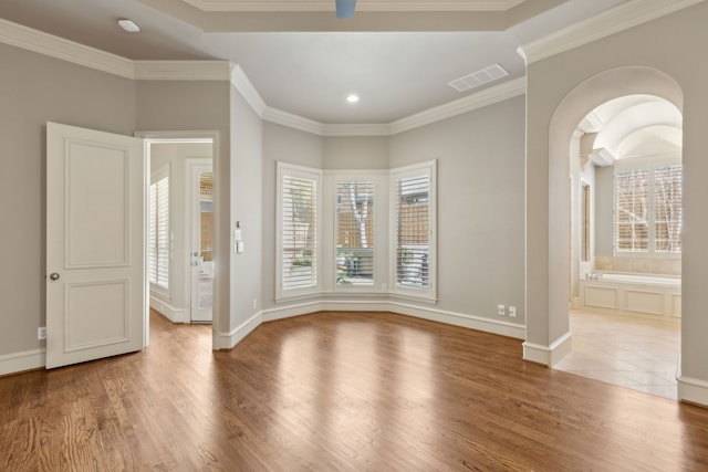 spare room with crown molding, visible vents, and wood finished floors