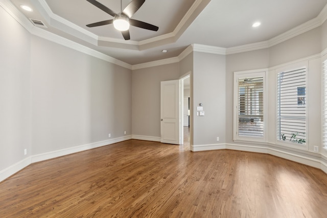 unfurnished room with a raised ceiling, ornamental molding, a ceiling fan, wood finished floors, and baseboards