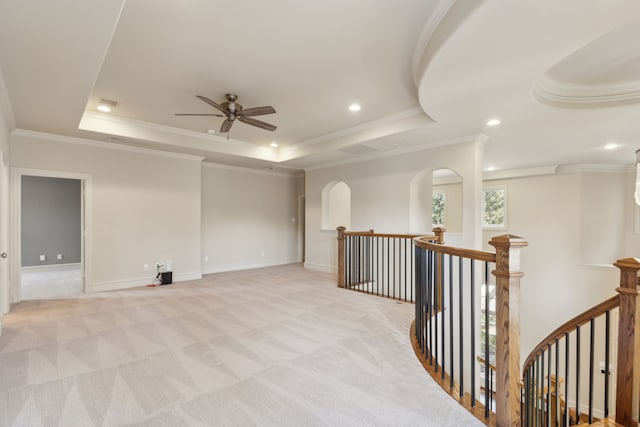 empty room featuring a tray ceiling, crown molding, recessed lighting, light carpet, and baseboards