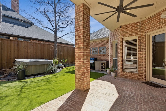 view of patio featuring a ceiling fan, fence, a hot tub, and grilling area