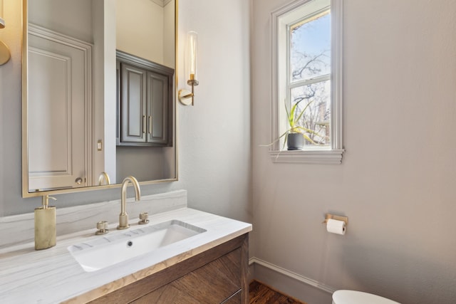 half bath featuring a healthy amount of sunlight, baseboards, and vanity