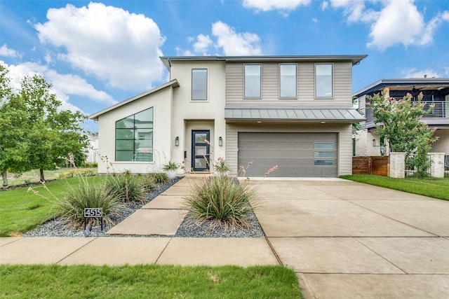 modern home with driveway, metal roof, an attached garage, a standing seam roof, and a front yard