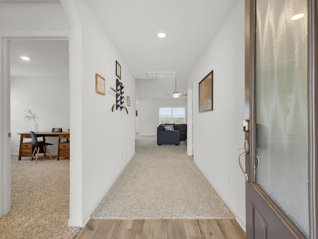 corridor with light carpet, light wood-style floors, visible vents, and recessed lighting