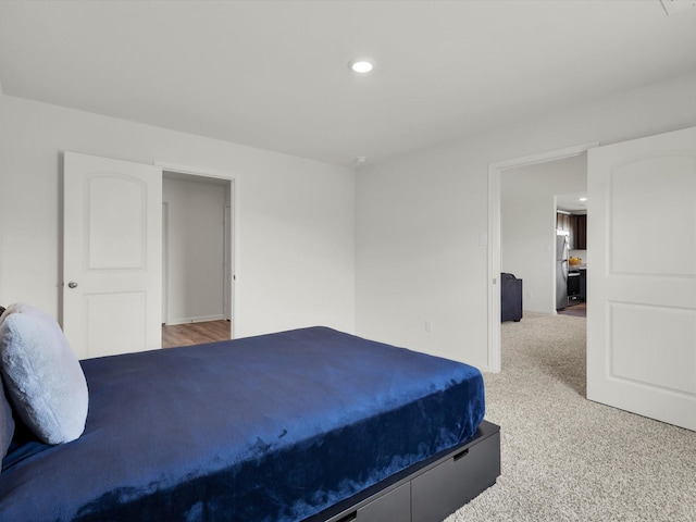 bedroom featuring light carpet, recessed lighting, and freestanding refrigerator