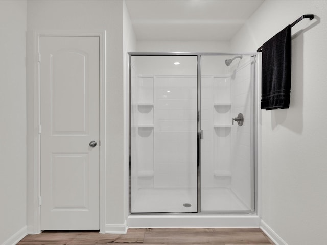 full bath featuring a stall shower, baseboards, and wood finished floors