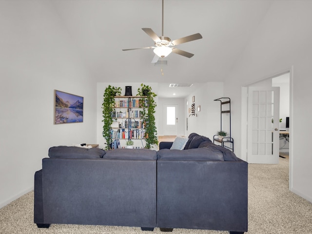 living area with visible vents, vaulted ceiling, a ceiling fan, and light colored carpet