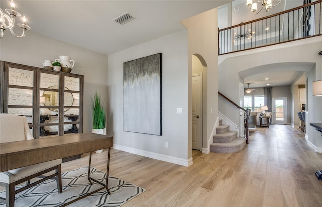 home office featuring baseboards, visible vents, arched walkways, light wood-type flooring, and a notable chandelier