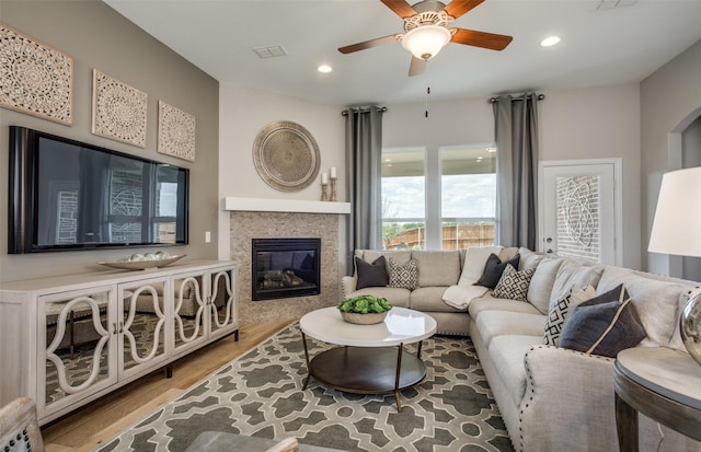 living area with recessed lighting, visible vents, a glass covered fireplace, ceiling fan, and wood finished floors