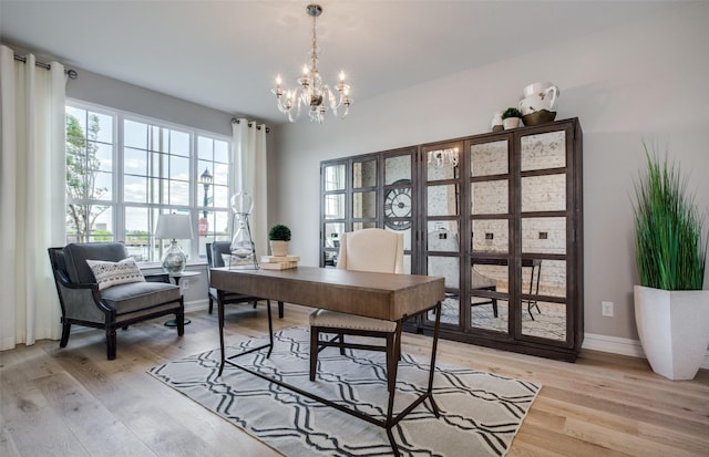 home office featuring light wood-style floors, a notable chandelier, and baseboards