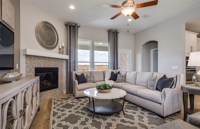 living area with recessed lighting, a ceiling fan, visible vents, a tiled fireplace, and dark wood finished floors