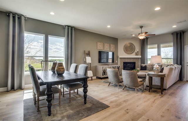 dining room featuring recessed lighting, a glass covered fireplace, visible vents, and light wood-style floors