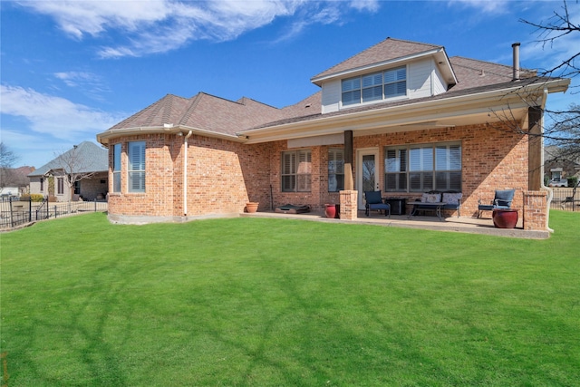 back of property with brick siding, a lawn, a patio, and fence