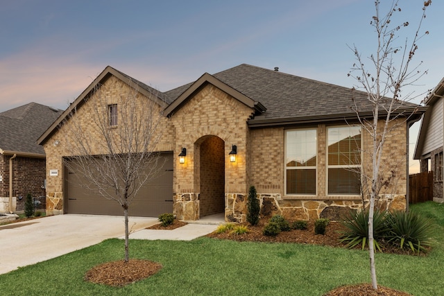 view of front of home featuring a garage, concrete driveway, stone siding, roof with shingles, and brick siding