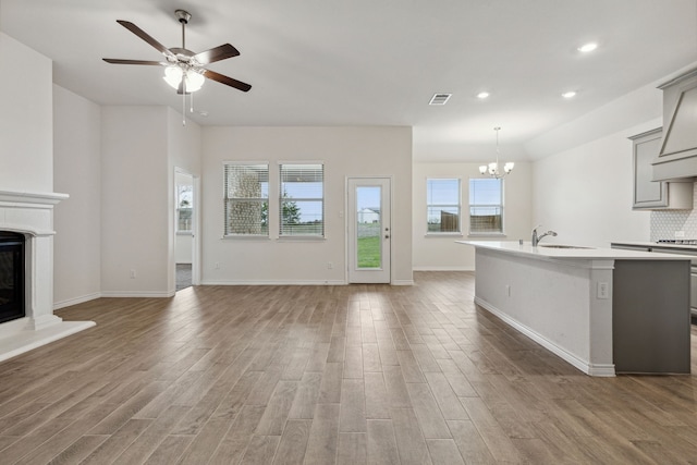 kitchen with a sink, open floor plan, light countertops, gray cabinets, and a glass covered fireplace